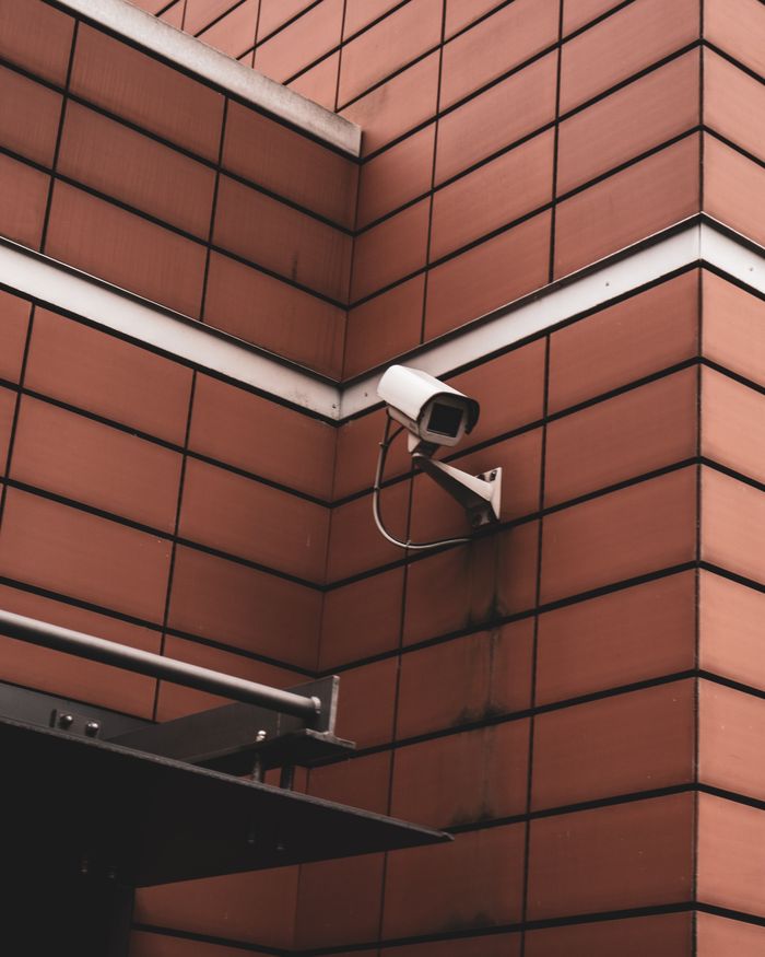 Security camera monitoring a red brick building exterior, symbolizing modern surveillance in Germany.
